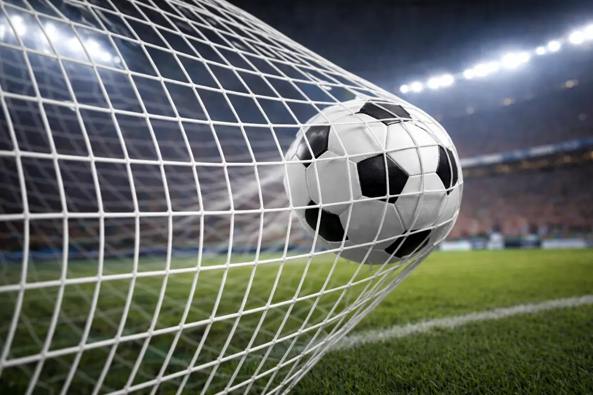 Ballon de football entrant dans les filets d'un but dans un stade éclairé